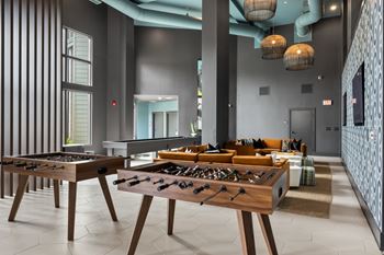 A foosball table is in the middle of a room with a couch and a rug.
